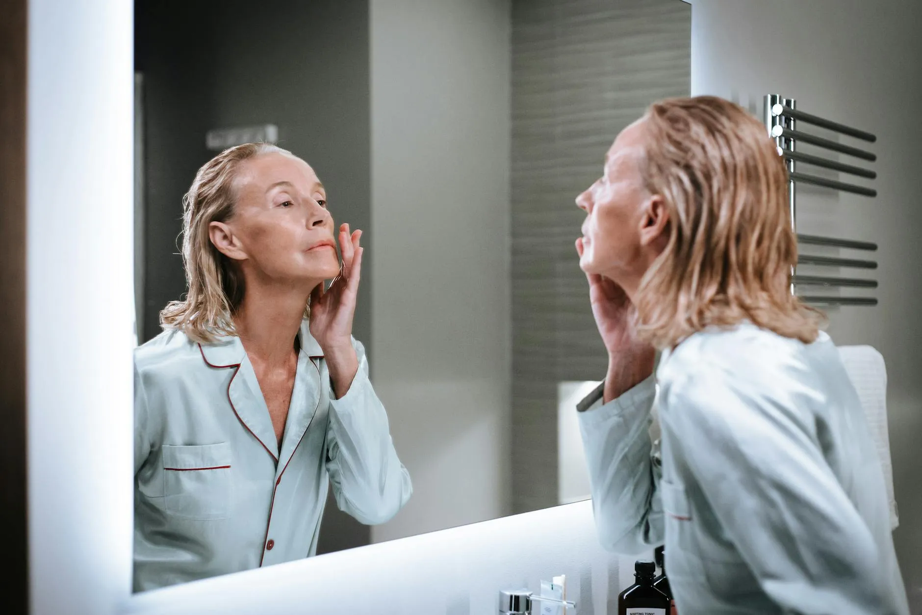 Žena nanášející krém před zrcadlem